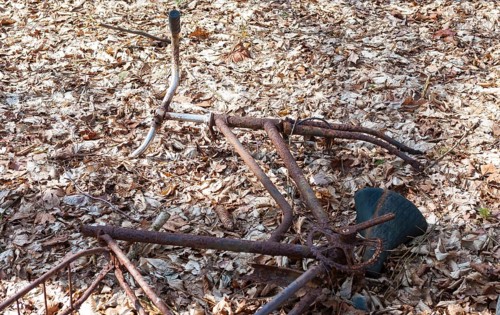Destroyed, rusty bicycle wreck in the forest, broken Dutch bike, old bicycle lying damaged on the