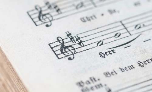 Close-up of a sheet music with musical symbols and text in black and white, historical, old,