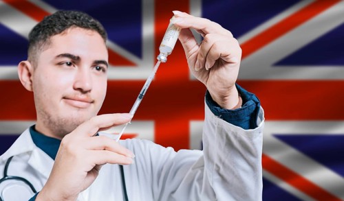 Doctor holding syringe on United Kingdom flag background. Medical professional holding syringe with