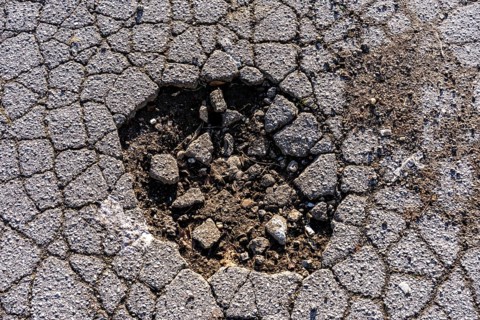 Pothole, asphalt surface, floor, with many small cracks, roadway, parking lot
