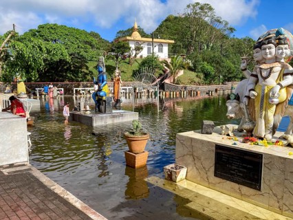 Shore of Sacred Lake Ganga Talao in crater of extinct volcano with blue sculpture of deity Shiva