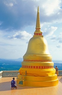 People, man praying, chedi in Wat Tam Sua monastery, which is partly on the top of a mountain,
