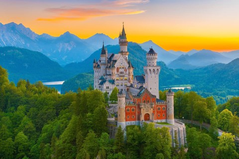 Majestic Neuschwanstein Castle against an alpine backdrop at sunset with plenty of nature and