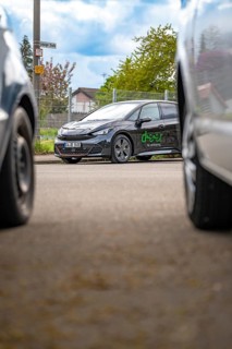 A modern car is parked between other vehicles on an urban road, Cupra electric car, e-car sharing,