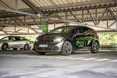 A dark car is parked under a roof in a modern parking garage, electric car Cupra, e-car sharing,