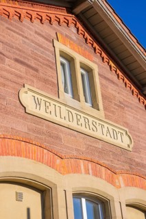 Brick building with Weilderstadt lettering under blue sky, Weil der Stadt railway station, Germany