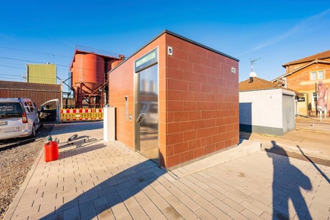Modular brick-colored building next to parked vehicle, Weil der Stadt railway station, Germany