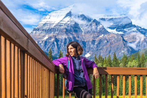Female hiker is taking a break and enjoying breathtaking view of mount robson, the highest peak in