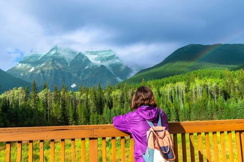 Female hiker with a backpack enjoying the breathtaking view of mount robson, the highest peak in