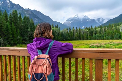 Female hiker with backpack enjoying the scenic view of mount robson, the highest peak in the