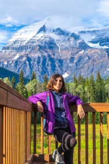 Female hiker is taking a break on a wooden platform, enjoying the breathtaking view of mount