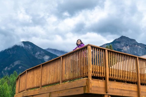 Tourist is standing on a wooden viewpoint, embracing the majestic scenery of mount robson in the