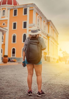 Travel woman in a tourist square at sunset, Granada, Nicaragua. Back view of tourist girl walking