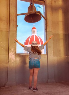Travel woman spreading arms at viewpoint in Granada, Nicaragua Back view of tourist girl spreading