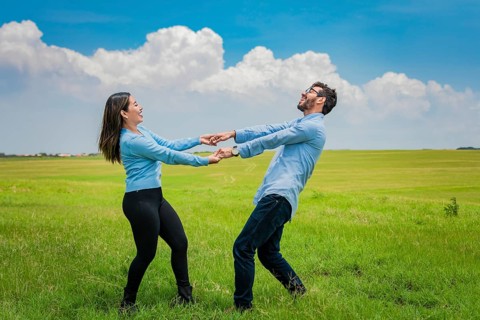 Happy couple spinning in a circle in the field, happy young couple spinning and playing in the
