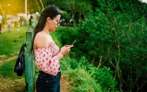 Latin woman checking her cell phone, pretty girl in glasses checking her cell phone