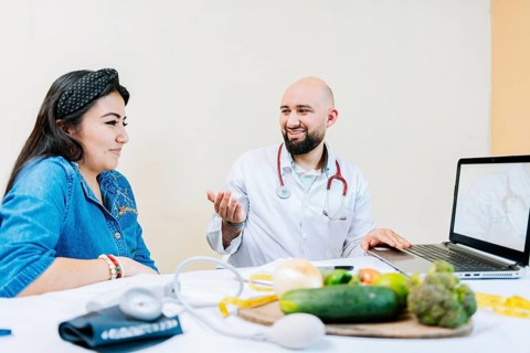 Smiling nutritionist explaining to a female patient, Nutritionist man talking to woman patient in