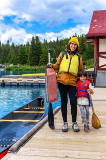 Mother and son holding paddles and wearing life jackets, getting ready for a canoe trip on the