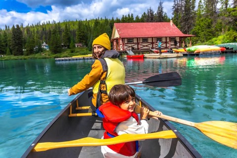 Mother and son are paddling a canoe on the beautiful turquoise maligne lake in jasper national