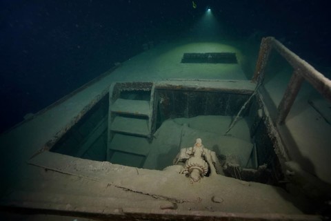 Diver examines a lediwreck, wreck of a lediship, ledi ship, cargo ship for mass freight, bulk