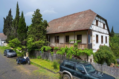 Half-timbered rural house with parked car and motorbike on a cobblestone street, Schwabenstraße 15,