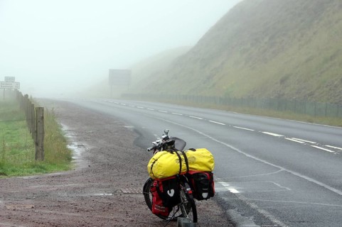 Bicycle with luggage on a foggy and deserted country road, cycle tourism, adventure, Shetlands,