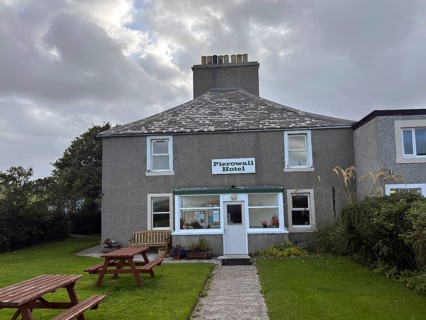 Classic hotel view under cloudy sky with green surroundings and picnic tables, only hotel on