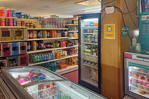 Small supermarket with fully stocked shelves and refrigerated products, shop on Westray Island,