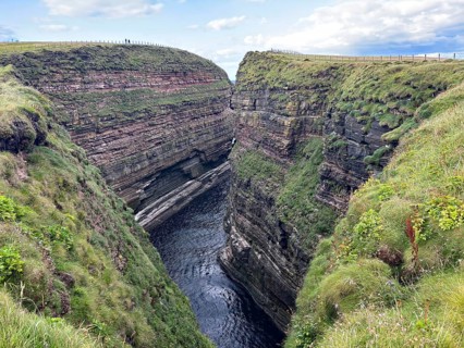 Deep gorge between steep cliffs with green grass covers, Duncansby Stacks, John O' Groats Scotland,