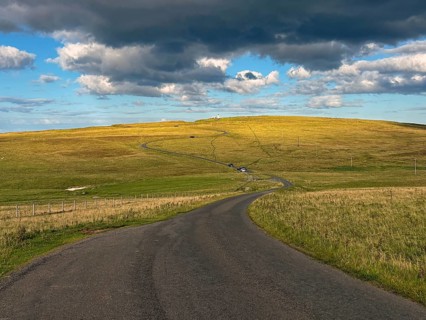 Road running through rolling fields under cloudy sky at dusk, Duncansby Stacks, John O' Groats