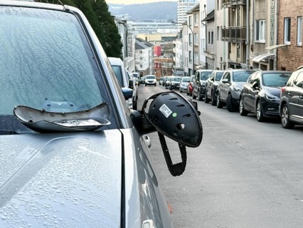 A car on the side of a steep residential street. The vehicle's left wing mirror is severely damaged