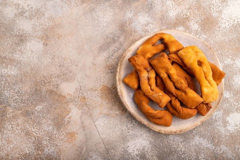 Crunchy biscuit Brushwood cookies sprinkled with powdered sugar on brown concrete background, top