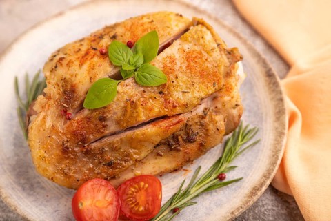 Fried Turkey Thigh with spices and rosemary on plate on brown concrete background and orange linen