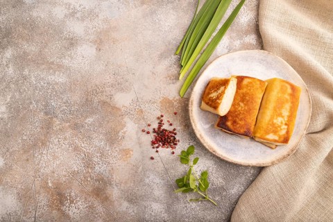 Fried crispy pancakes with meat and cheese on brown concrete background and linen textile. top