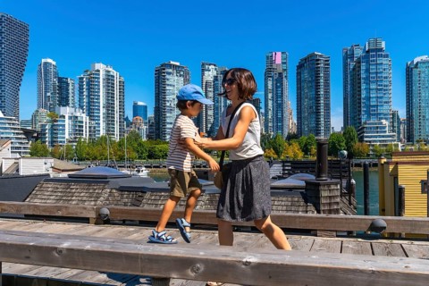 Mother and son enjoying a sunny day walking along the wooden boardwalk on granville island with the