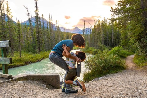 Mother embracing her son by the riverside in banff national park, surrounded by the stunning