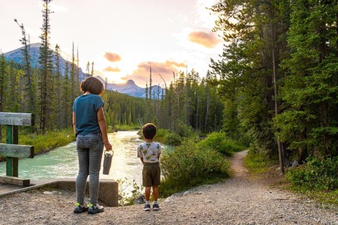 Mother and son enjoying breathtaking sunset view over river and mountains in banff national park,