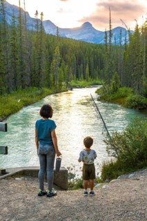 Mother and her son are enjoying the breathtaking view of a pristine river flowing through a lush