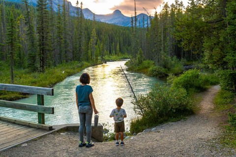 Mother and her son are enjoying a breathtaking sunset view over a pristine river flowing through