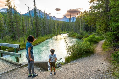 Woman points towards the majestic mountains in the distance as she and her son stand near a