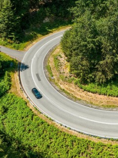 Car on a winding road in the forest, taken from a bird's eye view, Deer E-car sharing, Cupra