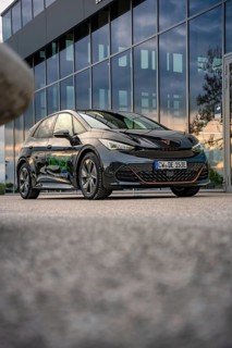 Black car in front of a modern building with glass façade, photographed on concrete floor, Deer