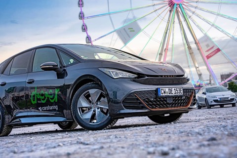 Modern cars in front of a big Ferris wheel at a trade show, Deer E-Car Sharing, Cupra electric car,