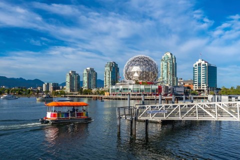 Passengers are enjoying a sunny day, riding an aquabus ferry in false creek with science world and