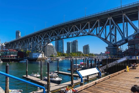Granville street bridge dominating the skyline over false creek with boats moored at the marina and
