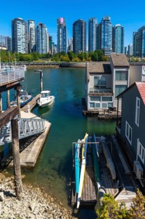 Kayaks resting on a wooden dock near floating homes, with a motorboat moored nearby and the
