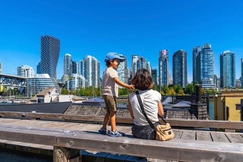 Sitting on a wooden bench at granville island market, a mother and son admire the stunning
