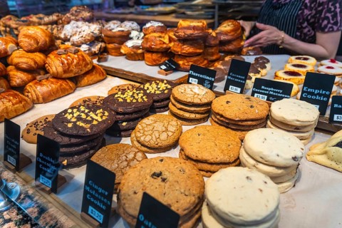 Freshly baked cookies and pastries are neatly arranged and labeled with prices in a bakery display