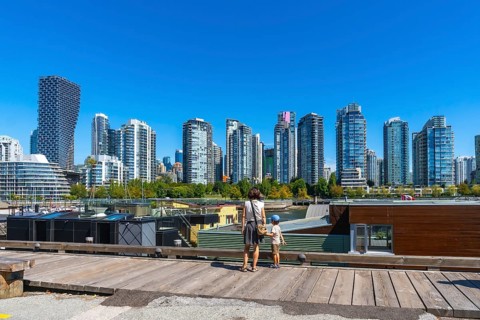 Mother and son standing on a wooden pier, admiring vancouver's modern skyline with high rise