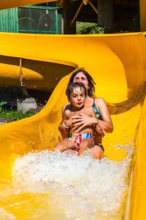 Mother and son enjoying a sunny day at a water park in vancouver, british columbia, sliding down a
